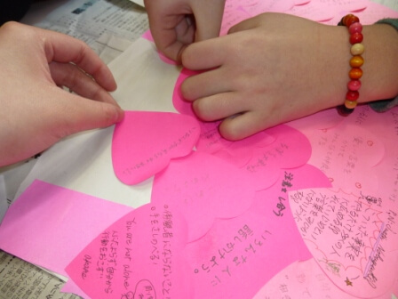 ピンク色のハート型の紙にメッセージを書く生徒さんたち